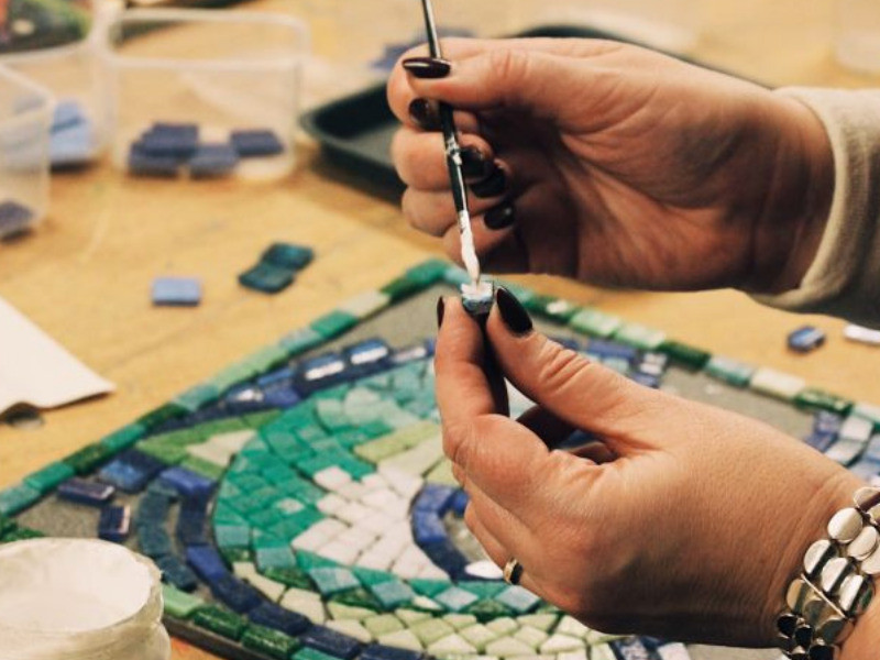 A person is crafting with glass tiles at a mosaic making workshop with Art4Space